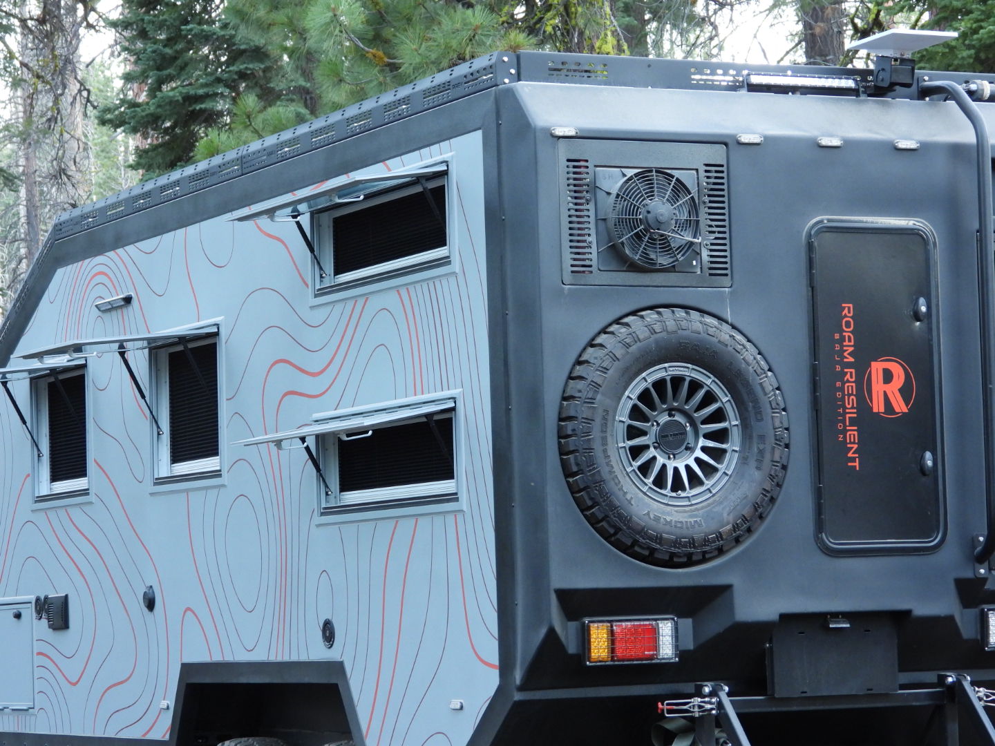 Baja Edition Bunk rear quarter in pine forest, roof fan, spare tire and topographic wrap
