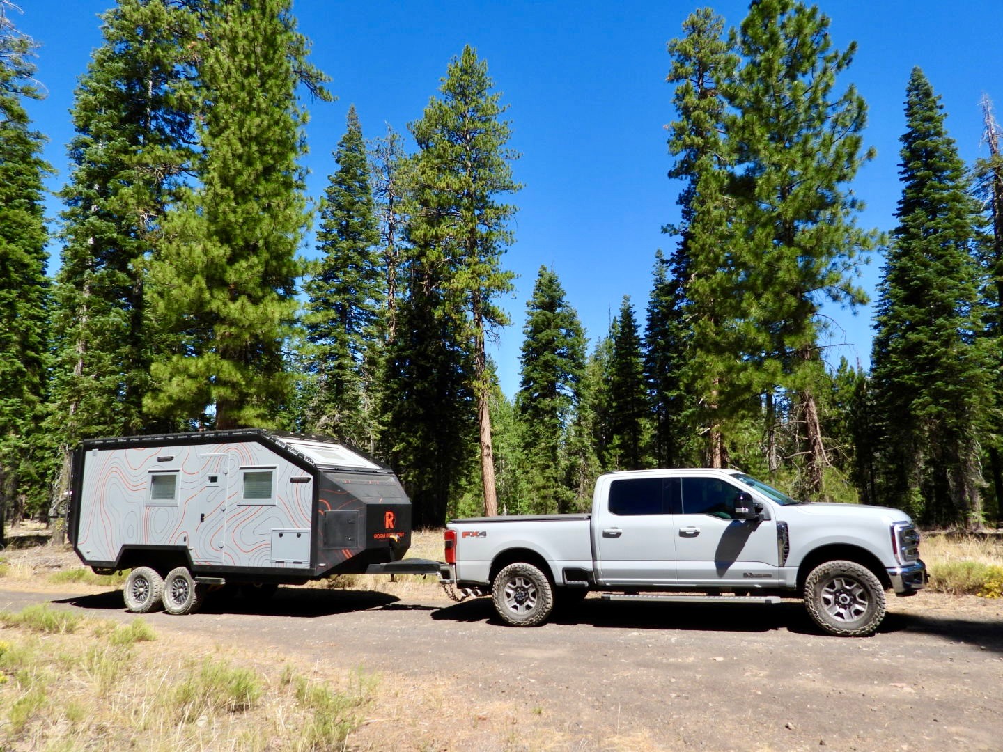 Baja Edition Bunk under tow by a Ford F-250 on a forest road under clear sky
