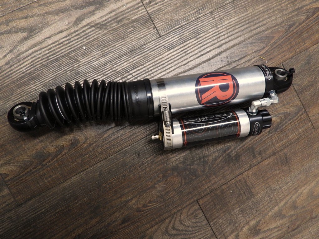 Radflo RREV remote-reservoir shock on the shop floor, bellows-protected shaft and braided reservoir line