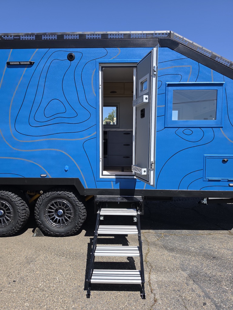 Aluminum fold-out steps at the Titan Edition's open entry door, tandem off-road wheels alongside