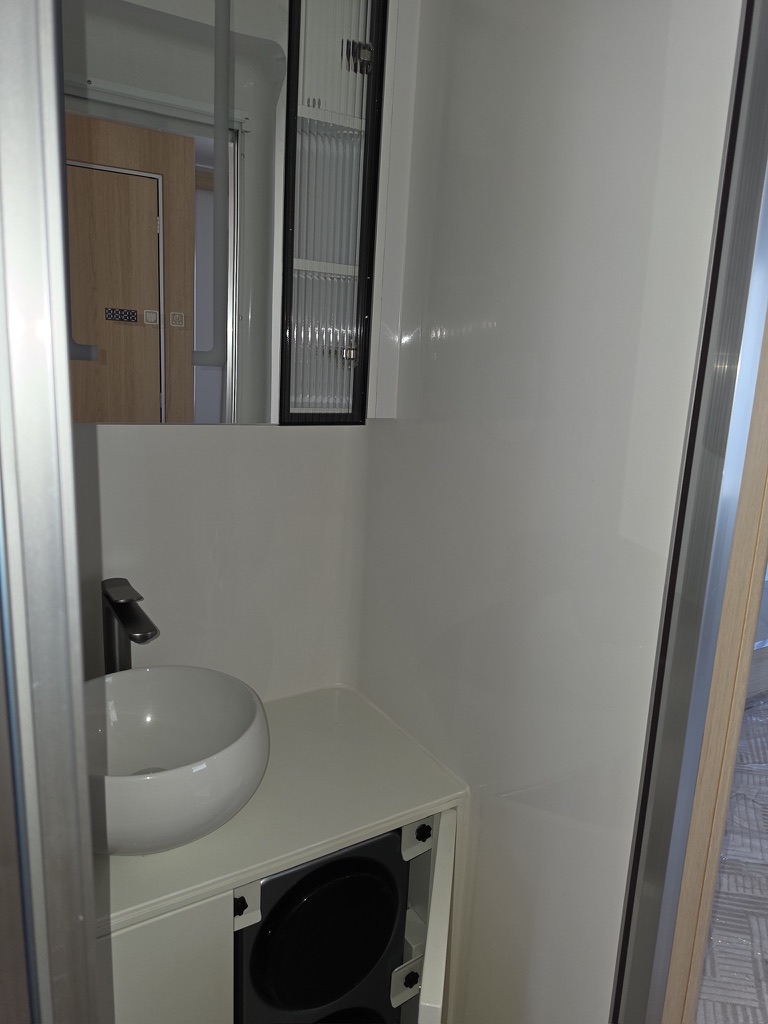 Compact washroom with a white vessel sink, matte black tap and mirrored cabinet above the open vanity bay