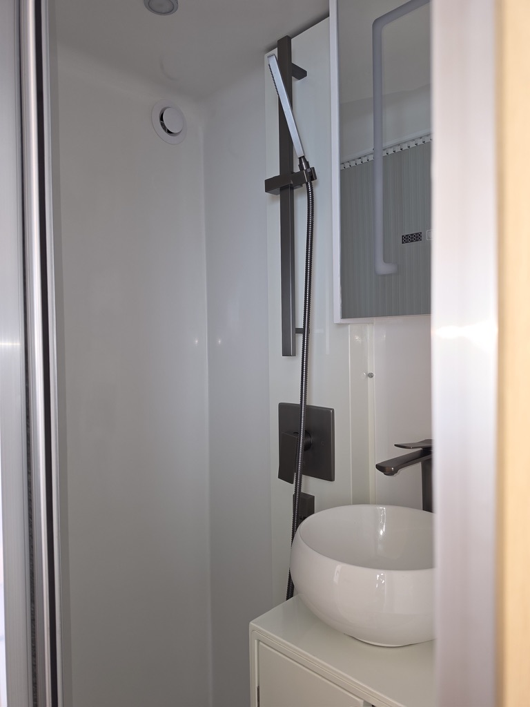 Wet bath with a vessel sink, gunmetal handheld shower on a slide bar and a mirrored cabinet